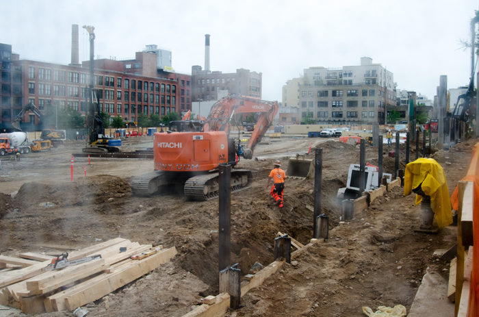 Current excavations at the site, observed through the construction fence, are part of an environmental cleanup (Photo by Chesher Cat for The Bridge)