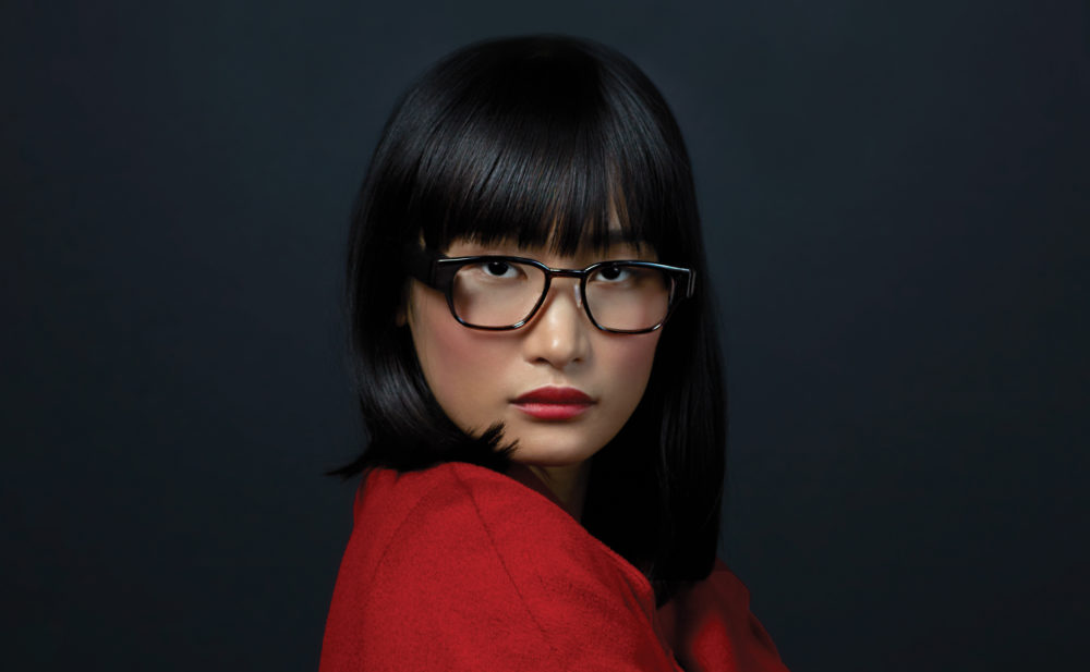 A model wears the classic version of the glasses, in black. They can be fitted with either prescription or non-prescription lenses